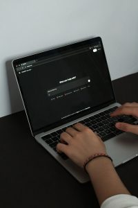 A person typing on a laptop with an AI tool open in a dark-themed browser window.